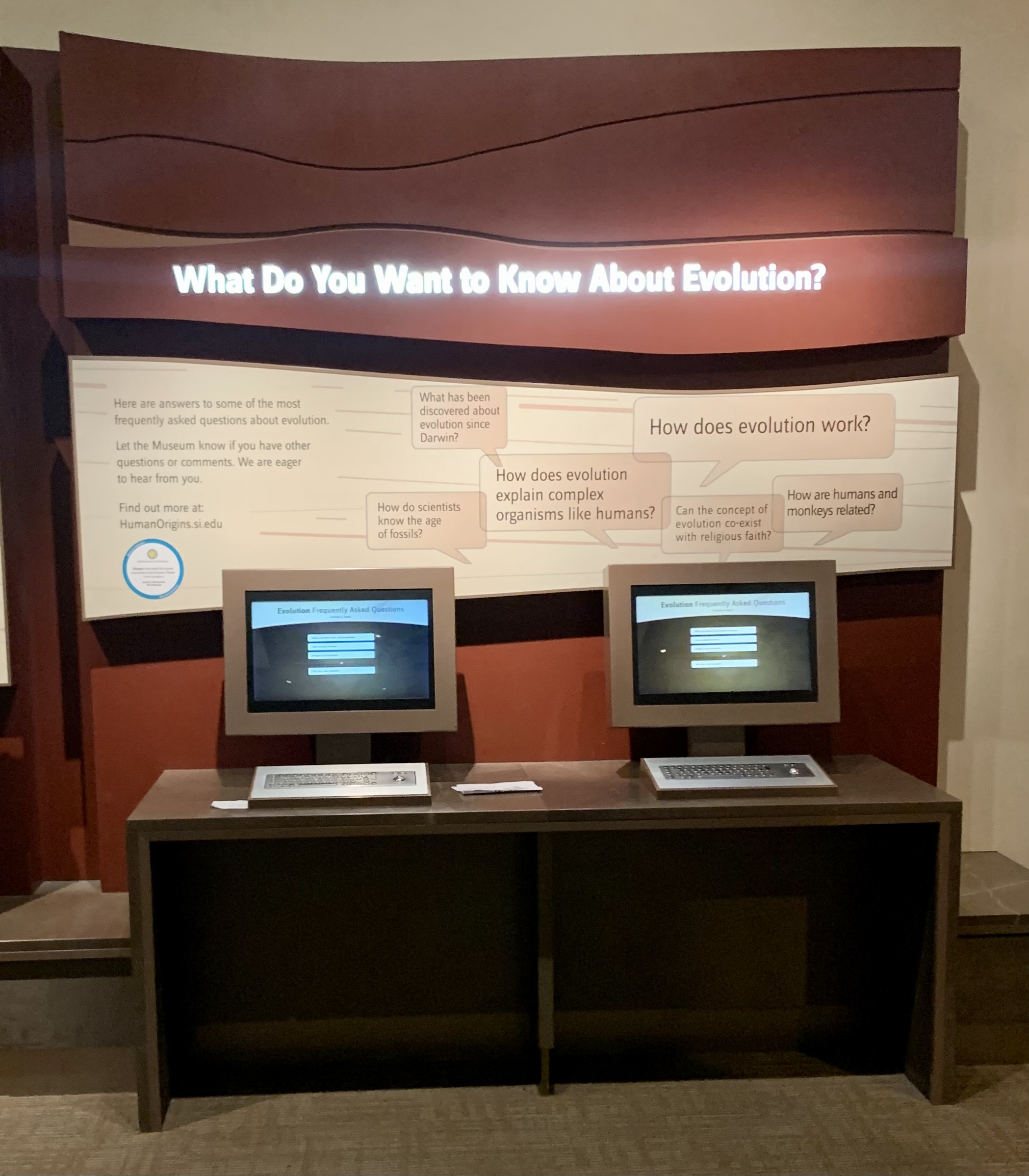 Photo shows a zoomed out view of the Evolution FAQ computers and the question above the computers reads: what do you want to know about evolution?