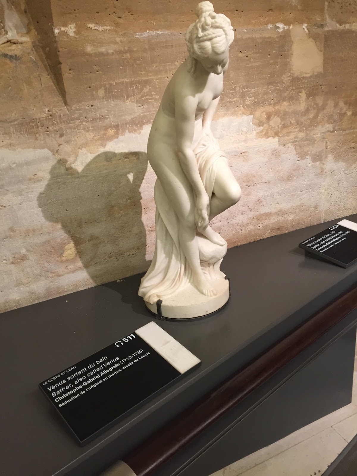 A picture of a small white statue of a woman who is bending down to dry herself off after a bath. This is a reproduction of Allegrain's *Venus After the Bath* which can be touched by visually impaired visitors at the Louvre's tactile gallery